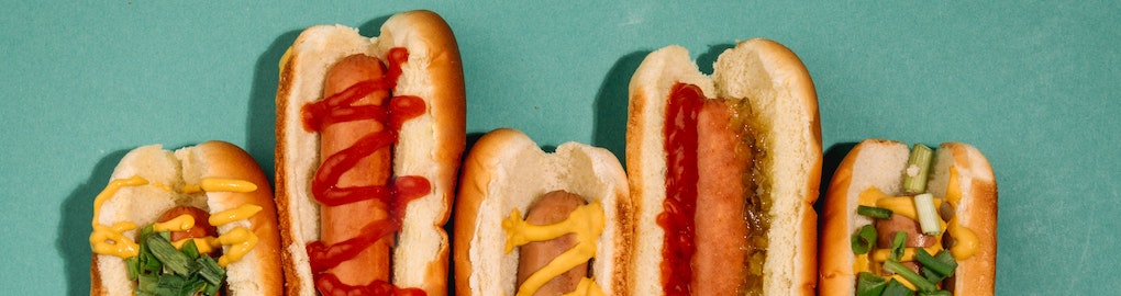 row of hot dogs with various sauces and condiments row of hot dogs with various sauces and condiments